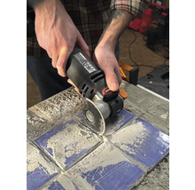 O persoană folosește un instrument multifuncțional pentru a tăia plăci.