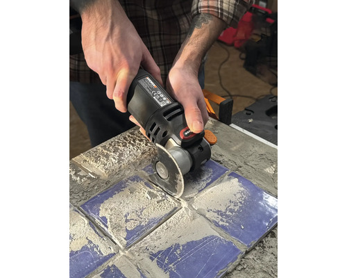 O persoană folosește un instrument multifuncțional pentru a tăia plăci.