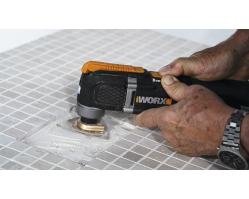 Imagine detaliată cu o persoană care lucrează la gresie cu un instrument multifuncțional, marca Worx