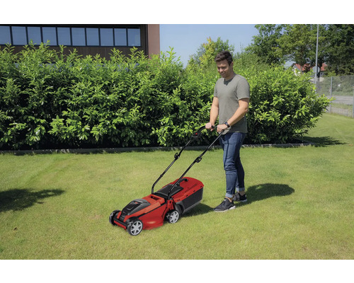 Bărbat tunde gazonul cu o mașină de tuns iarba în grădină.