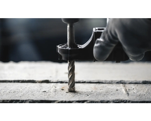 Prim-plan al unei mașini de găurit care găurește un perete de beton