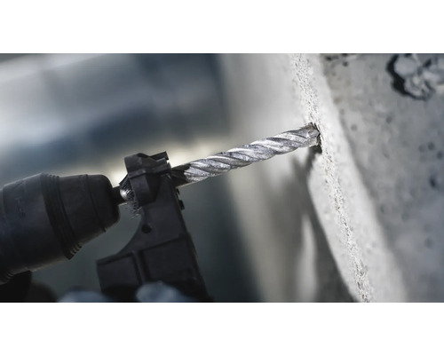 Prim-plan cu o mașină de găurit cu burghiu care găurește în beton
