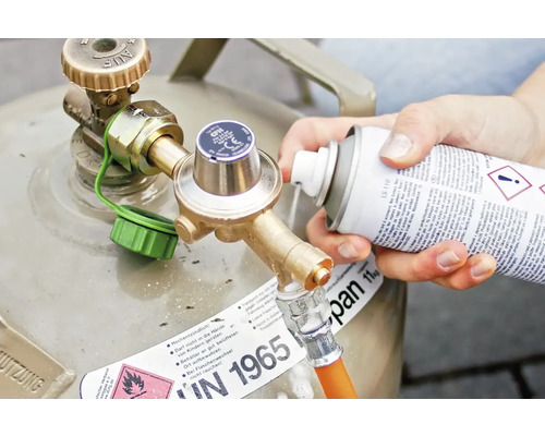 Persoană pulverizând detergent pe racordul buteliei de gaz