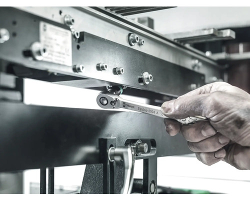 O mână operează o cheie cu clichet Wera Zyklop pe o construcție metalică