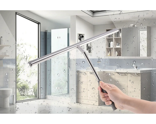 Mână care ține un racletă de geam pentru curățarea unei cabine de duș în baie.