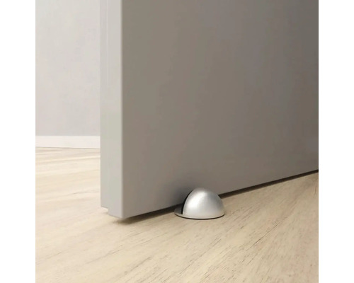 Opriitor de ușă metalic pe podea în fața unei uși