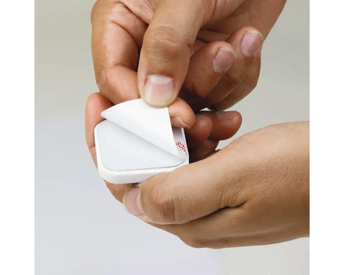 Mâini care îndepărtează folia de protecție de pe un suport adeziv