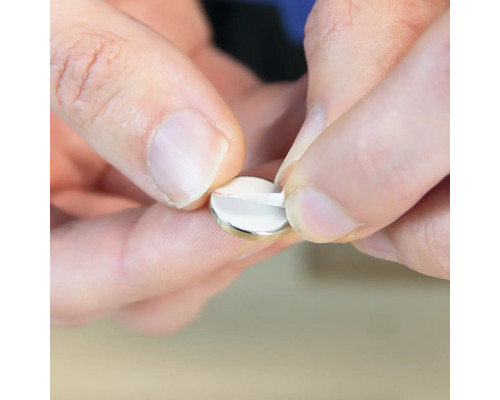 O persoană îndepărtează folia de protecție de pe un magnet disc.