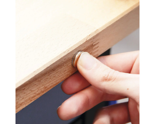 Mână fixează o închidere magnetică pe o scândură de lemn