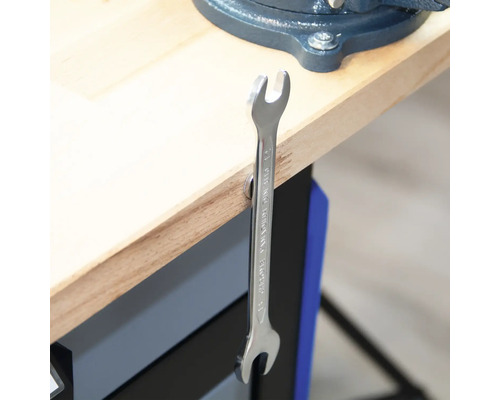 O cheie fixă atârnă de un banc de lucru.