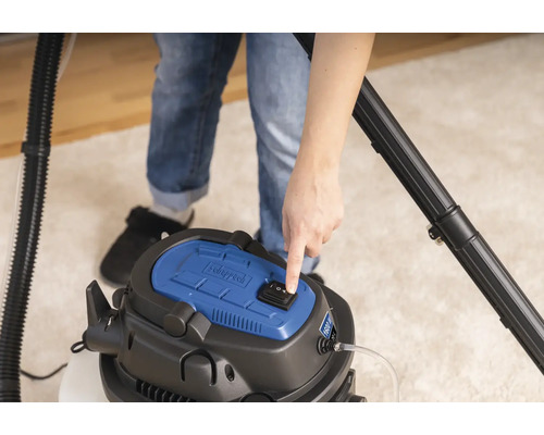 O persoană operează un aspirator umed uscat marca Scheppach