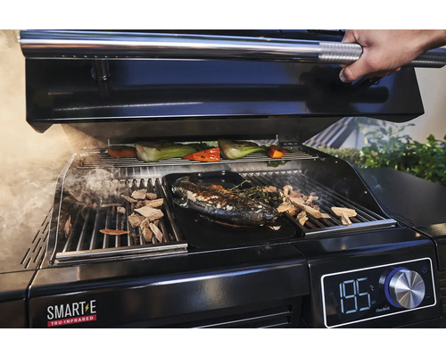 Se prepară un grătar cu pește, legume și așchii de lemn.