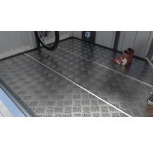 Podea metalică cu model în carouri într-un șopron, cu bicicletă, cizme și rafturi