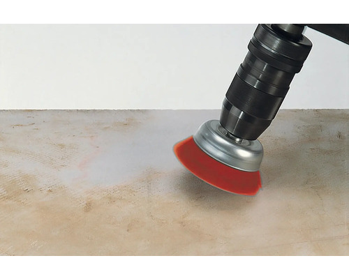 O mașină de găurit cu un accesoriu de perie curăță o suprafață.