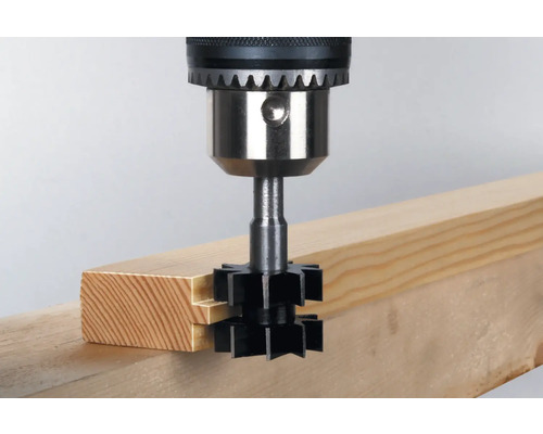 Freza de caneluri utilizată cu o mașină de găurit pe o scândură de lemn.