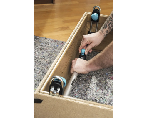 Un bărbat fixează un unghi de montaj Wolfcraft într-o cutie de lemn