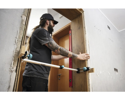 Bărbat care montează un toc de ușă cu o unealtă de montare