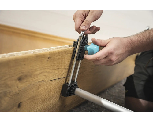 Utilizator care fixează o scândură de lemn cu o unealtă de montaj.