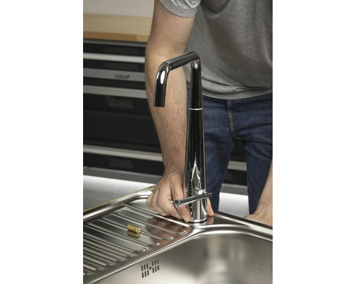 Un bărbat instalează o baterie într-o chiuvetă.