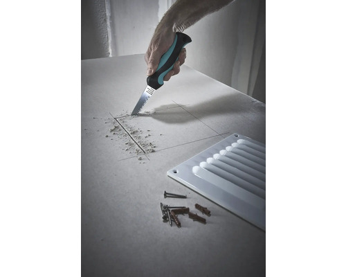 Un meșter taie o gaură într-o placă de gips-carton cu un fierăstrău pentru gips-carton, lângă o grilă de ventilație, precum și șuruburi și dibluri