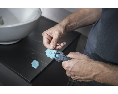 Un bărbat folosește un instrument de rosturi în baie pentru rosturile de silicon.