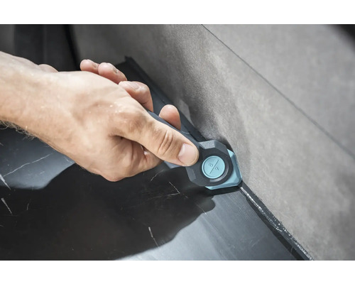 O mână folosește un instrument de netezire a rosturilor pentru a netezi rosturile dintre plăci.