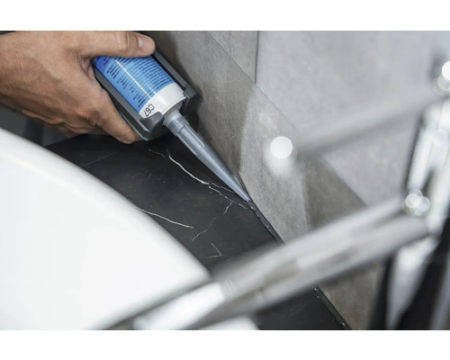 O persoană aplică silicon pe o suprafață de marmură.