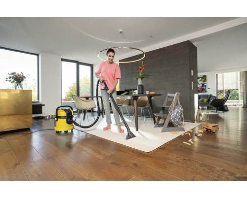 Femeie curăță covorul cu un aspirator cu spălare într-o sufragerie