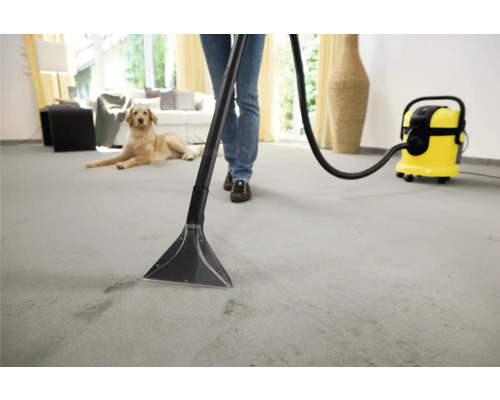 Persoană care curăță un covor cu un aspirator de curățare într-un mediu de viață luminos