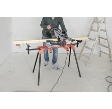 O persoană operează un ferăstrău circular pe o masă de tăiat, lângă o scară.