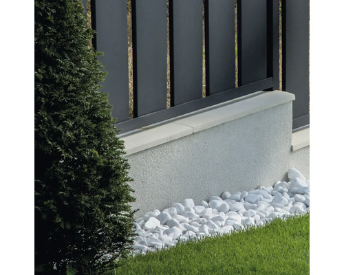 Prim-plan cu o grădină modernă cu gard, zid, pietriș decorativ și plante verzi