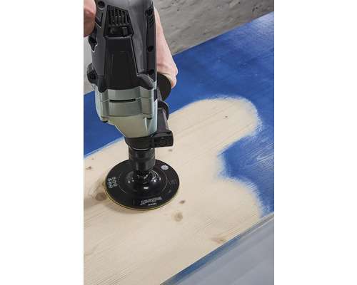 O persoană folosește un șlefuitor pentru a îndepărta vopseaua de pe o scândură de lemn.