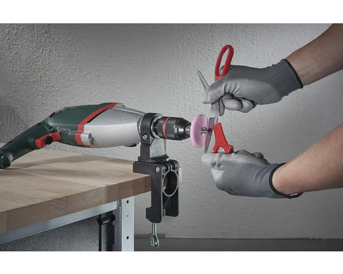 O mașină de găurit cu un atașament de șlefuire montat este folosită pentru a ascuți o foarfecă.