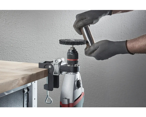 O mașină de găurit cu disc abraziv și piesă de prelucrat pe un banc de lucru.