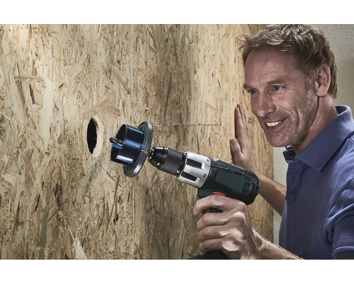 Un bărbat dă o gaură într-un perete de lemn cu un ferăstrău circular.