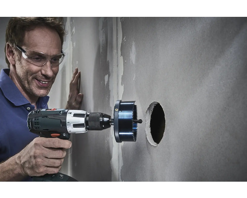 Un meseriaș găurește un perete cu un ferăstrău circular