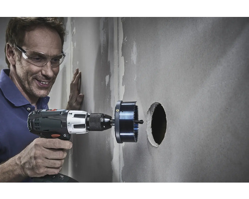 Un bărbat găurește un perete cu un ferăstrău circular