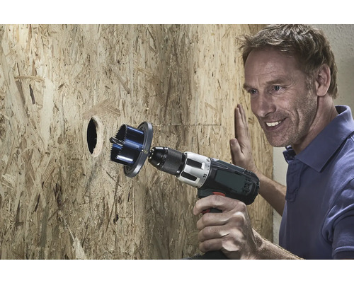 Un bărbat găurește o placă de lemn cu un ferăstrău circular.