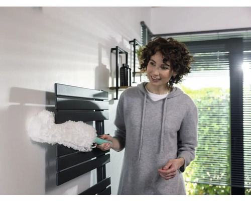 Femeie care curăță caloriferul cu un pămătuf