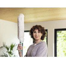 Femeie ține un pămătuf într-o cameră luminoasă.