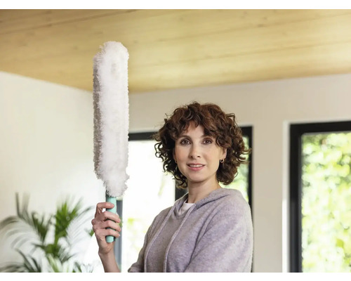 Femeie ține un pămătuf într-o cameră luminoasă.