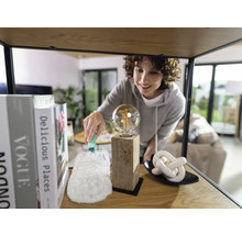 Femeie ștergând praful de pe un bec de pe un raft