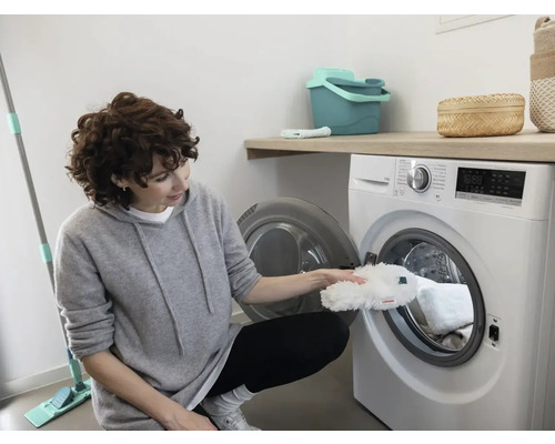 Femeie care pune un capac de mop într-o mașină de spălat