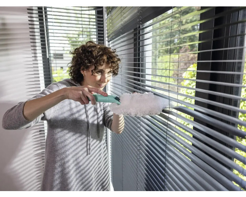 Femeie curăță jaluzele cu un pămătuf