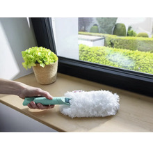 Persoană care ține un pămătuf cu mâner pentru curățare pe pervazul ferestrei