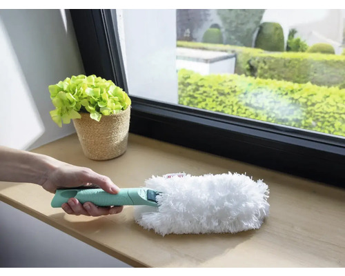 Persoană care ține un pămătuf cu mâner pentru curățare pe pervazul ferestrei