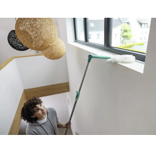 Femeie curăță pervazul ferestrei cu un pămătuf.