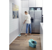 Femeie șterge podeaua cu un mop într-o bucătărie.