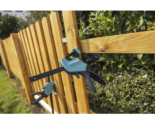 Clește Wolfcraft cu o mână pe un gard din lemn