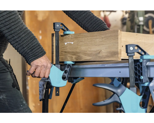 Un banc de lucru cu o menghină fixează o bucată de lemn.